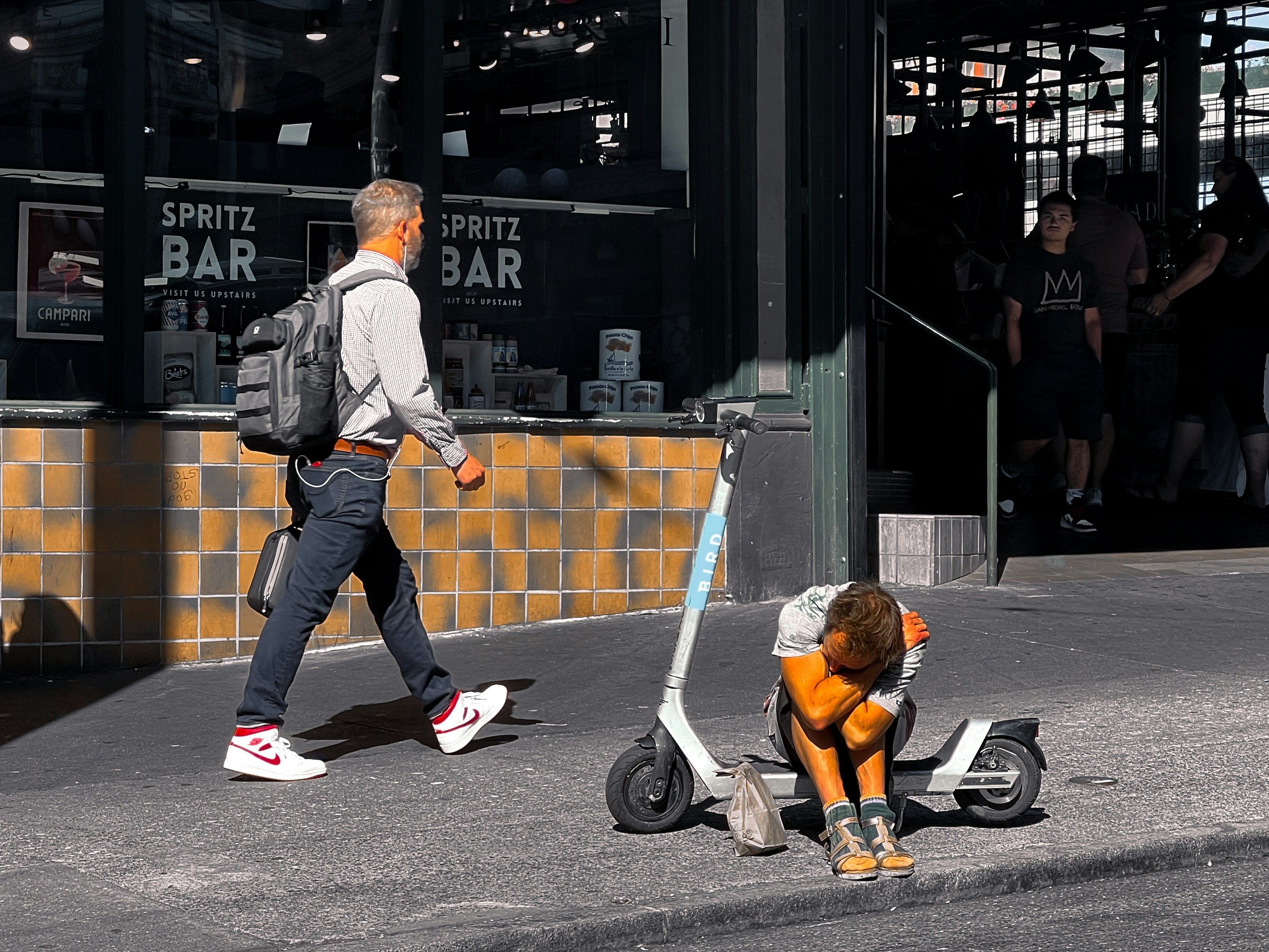 A man walking down a street next to a dog on a scooter