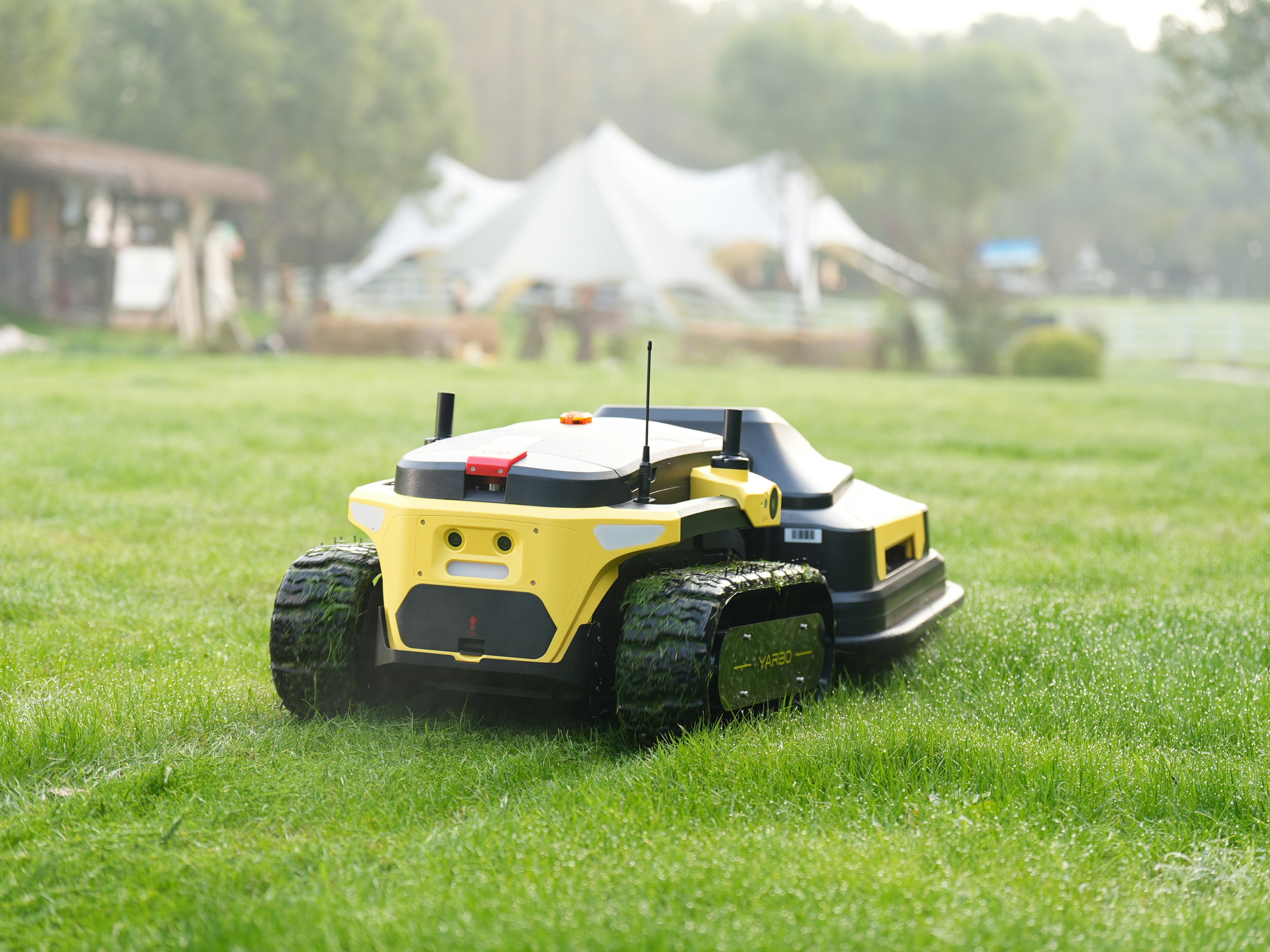 Robot lawnmower cuts grass in a backyard.